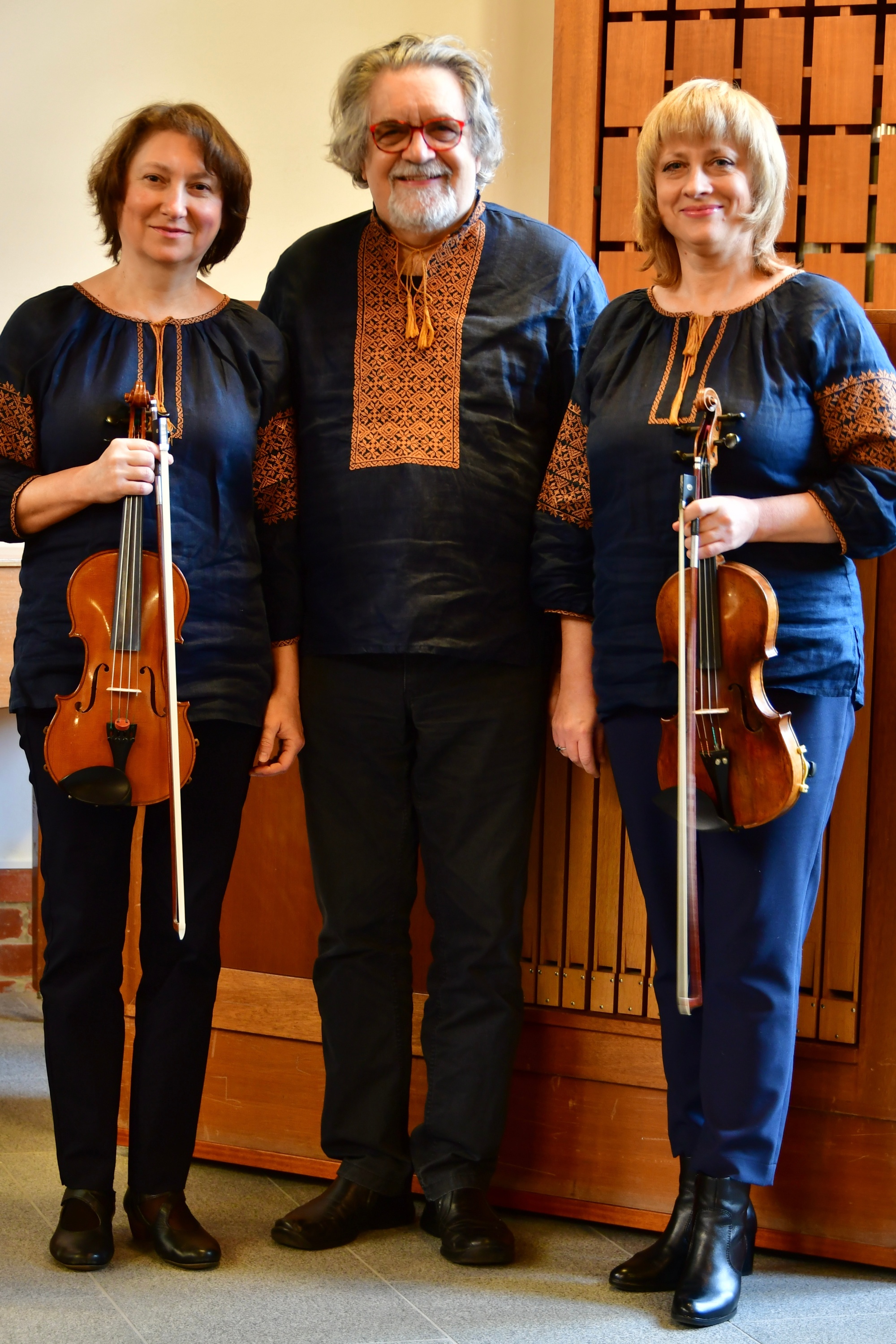 zwei Musikerinnen mit Violinen und dazwischen Organist stehend