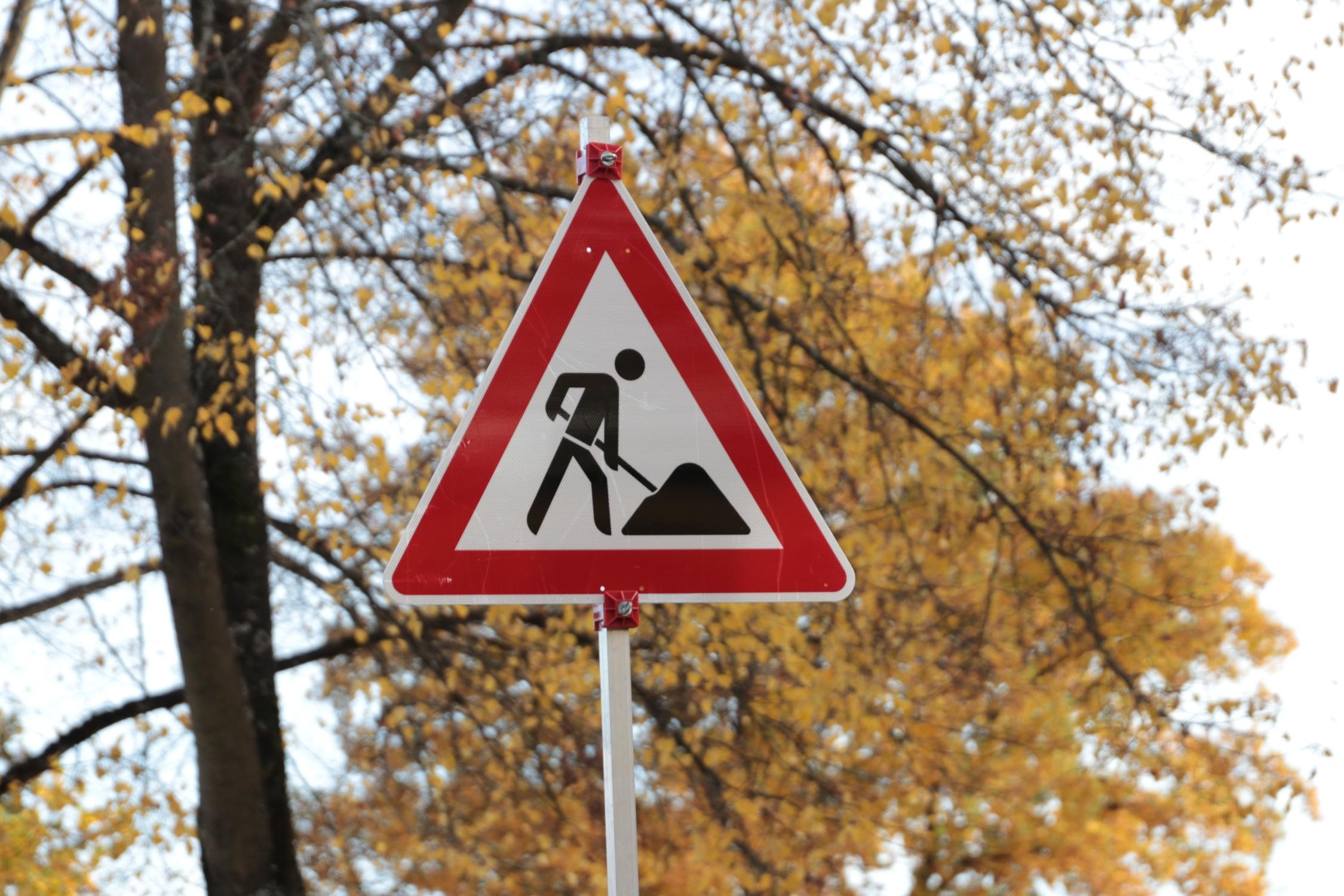 Verkehrsschild Baustelle vor herbstlichen Bäumen