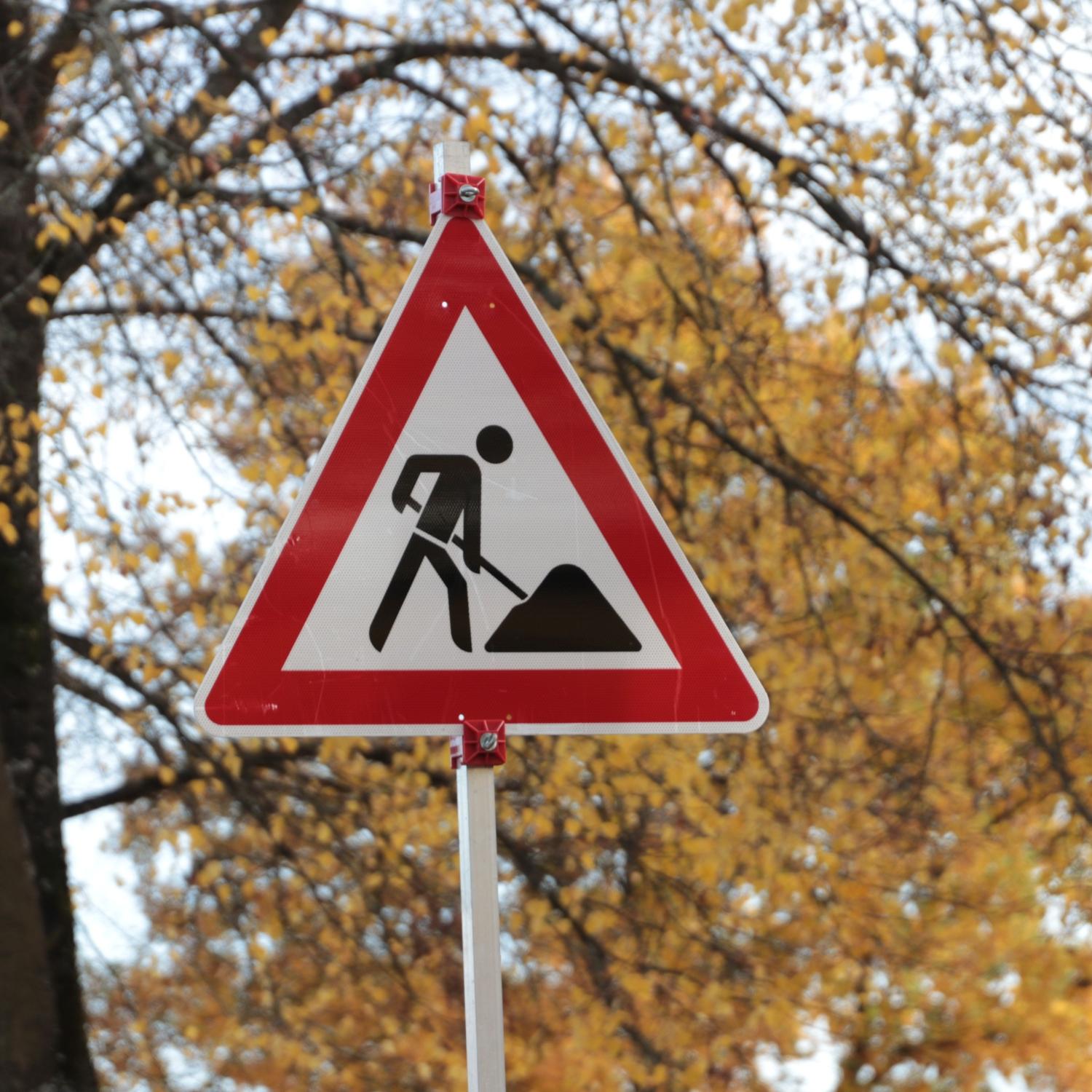 Verkehrsschild Baustelle vor herbstlichen Bäumen