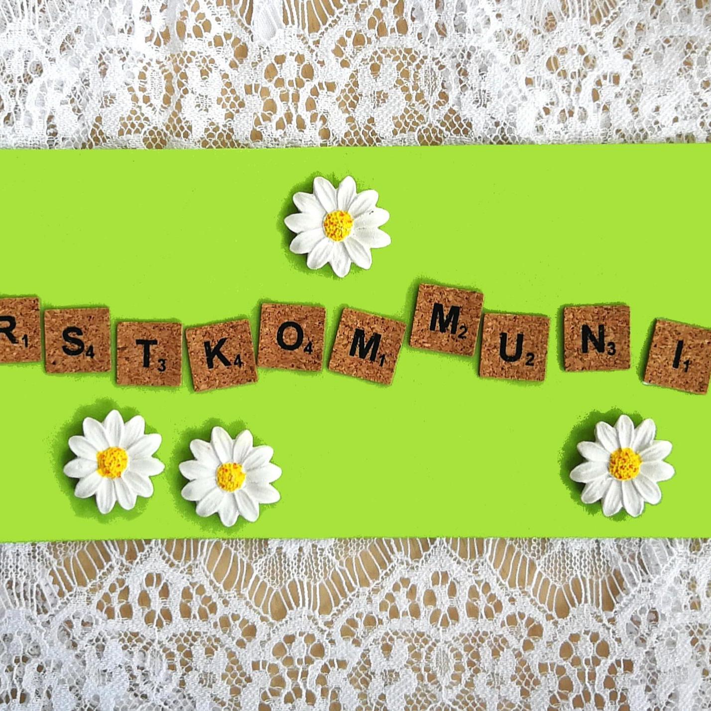 Holzbuchstaben „Erstkommunion“ auf grünem Hintergrund, umgeben von Gänseblümchen und Schmetterling.